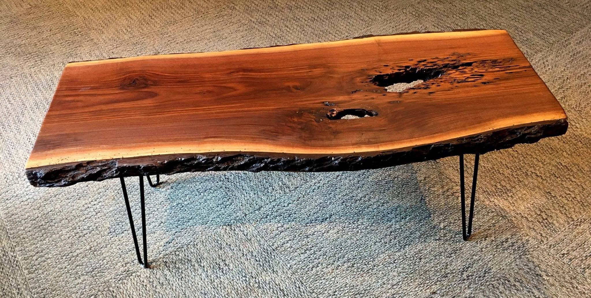 A black walnut live edge table/bench with black metal hairpin legs - tabletop has two open knot holes and live edge bark on both long sides