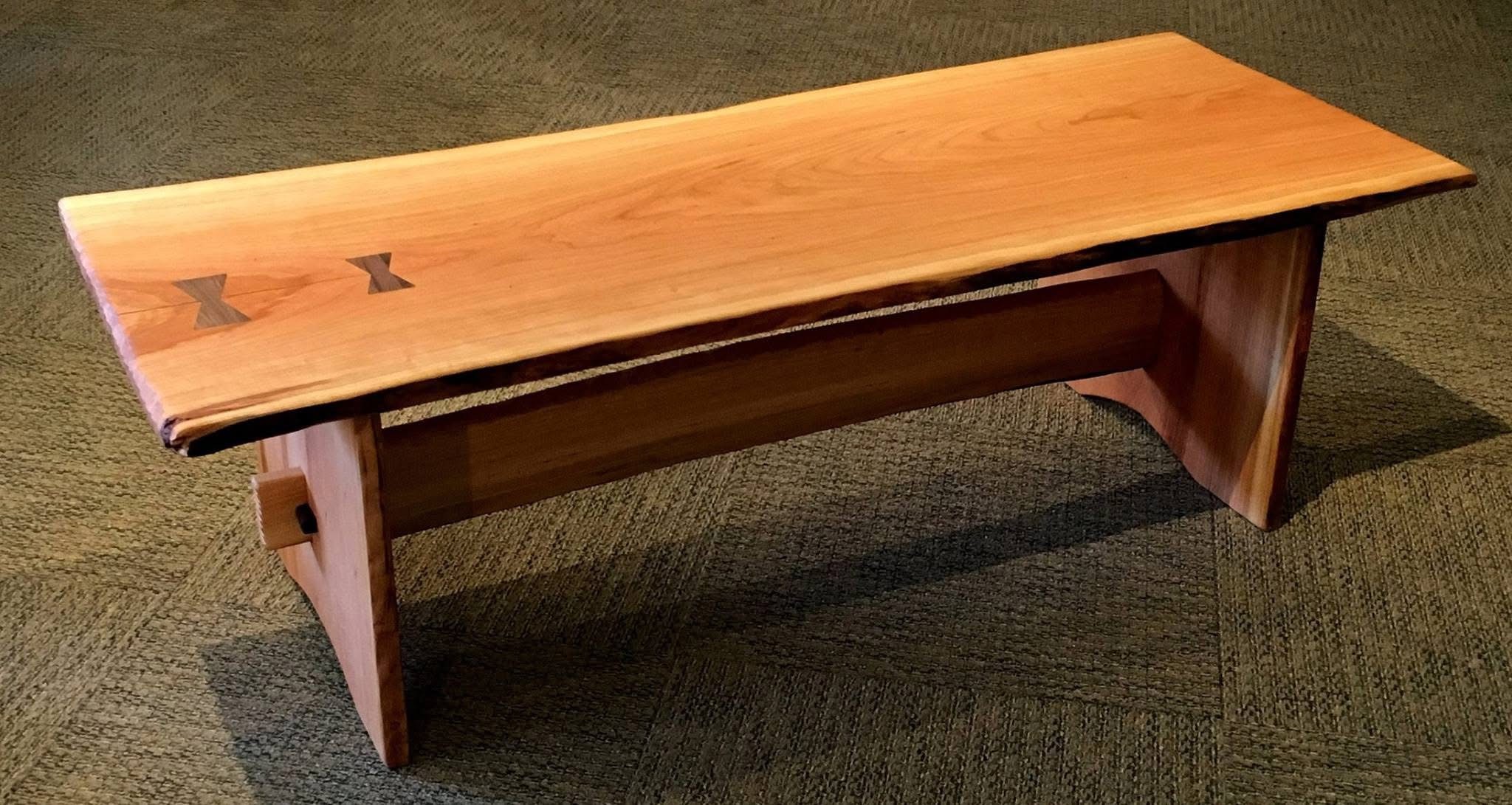 Cherry live edge bench with two black walnut butterflies on one side of the bench