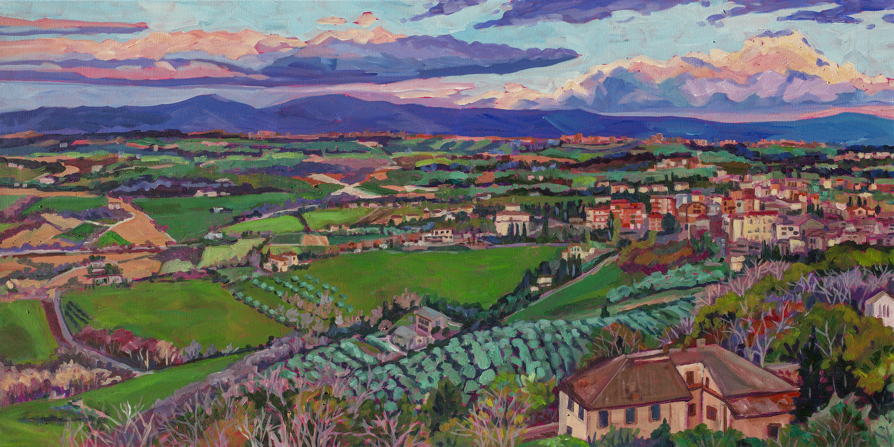 Panoramic view of countryside in Umbria Italy with fields village and olive groves and mountains in distance at sunset